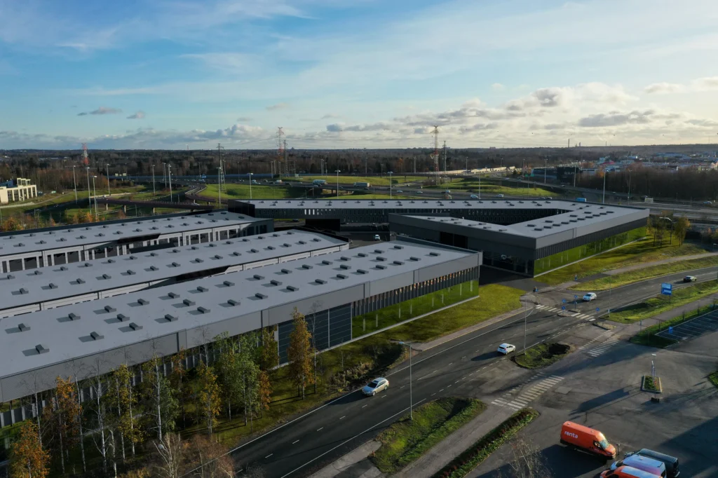 Aerial 3D rendering of a large distribution warehouse and its yard beside a motorway, Finland